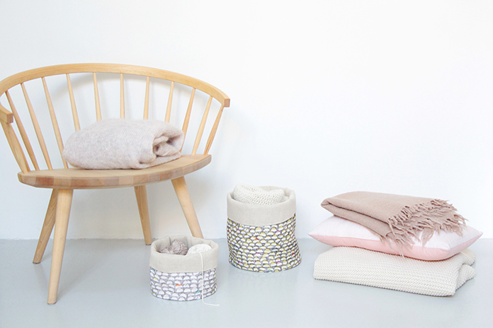 paniers de rangements, linge de lit sur chaise en bois clair